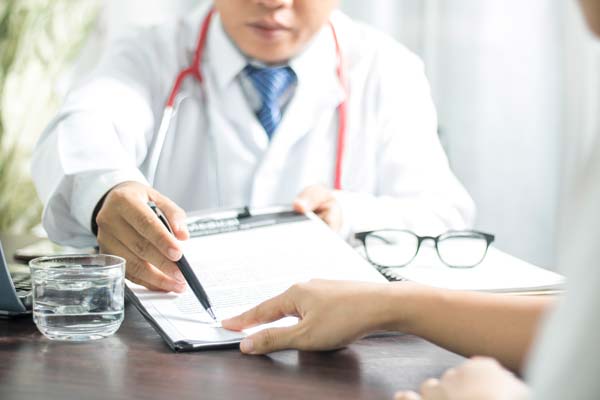 doctor points to form on clipboard
