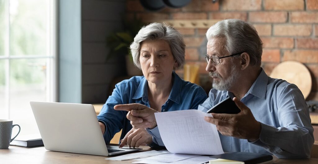 Older adults comparing paper bill with computer